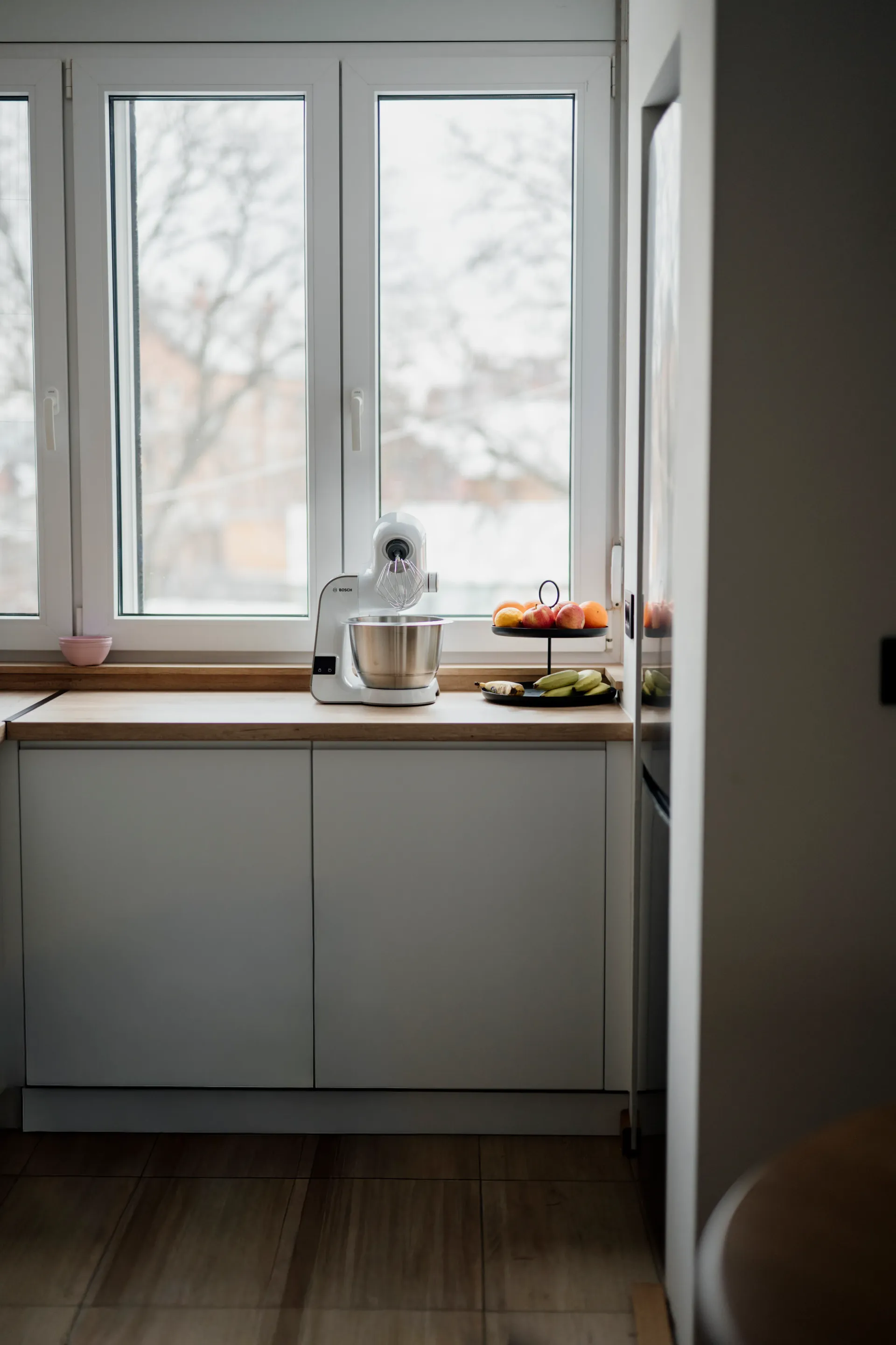 Cuisine lumineuse en hiver avec grande fenêtre laissant entrer la lumière naturelle